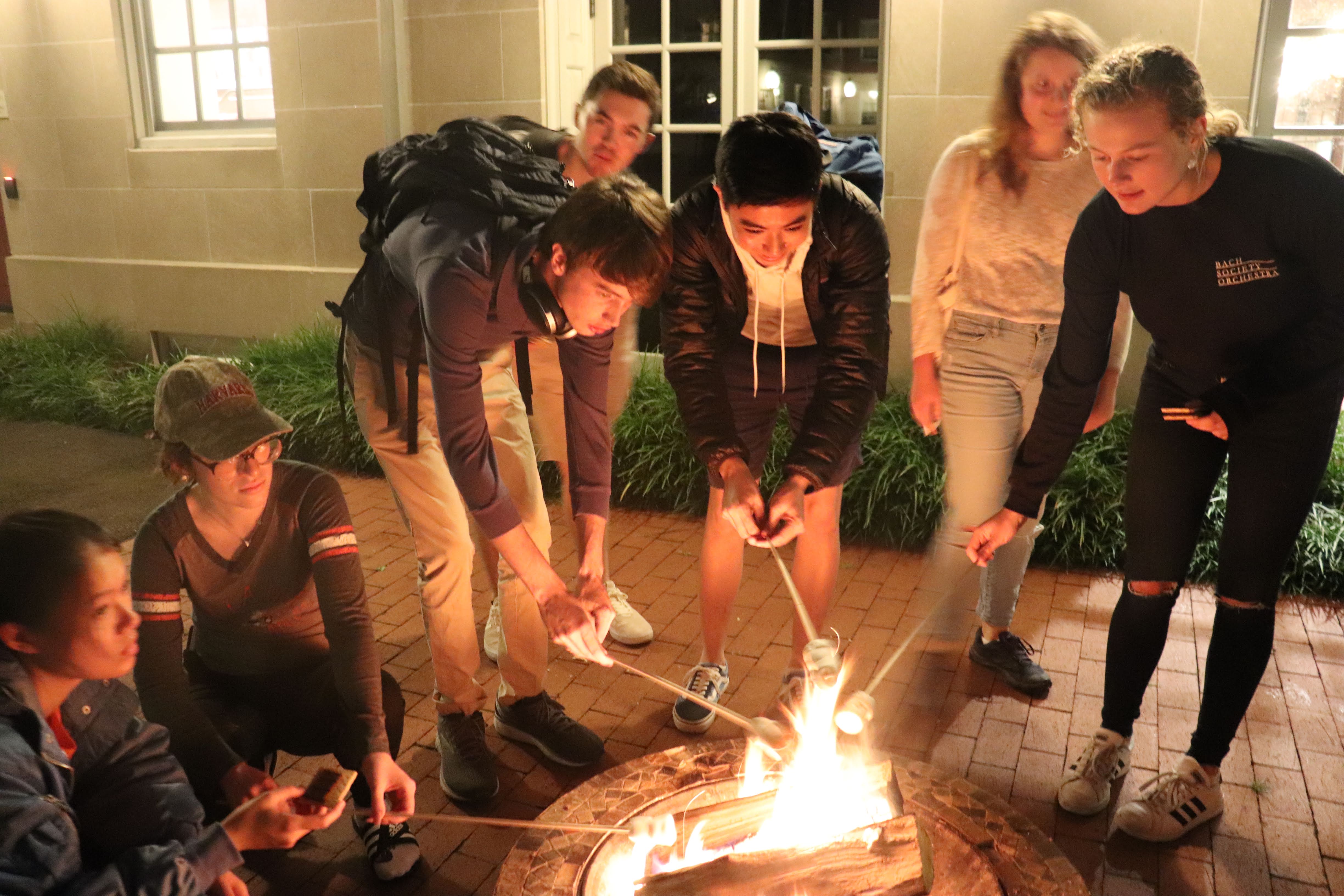 students roasting s'mores around a fire in the courtyard