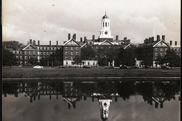 black and white photo of the Dunster tower reflecting onto the Charles river