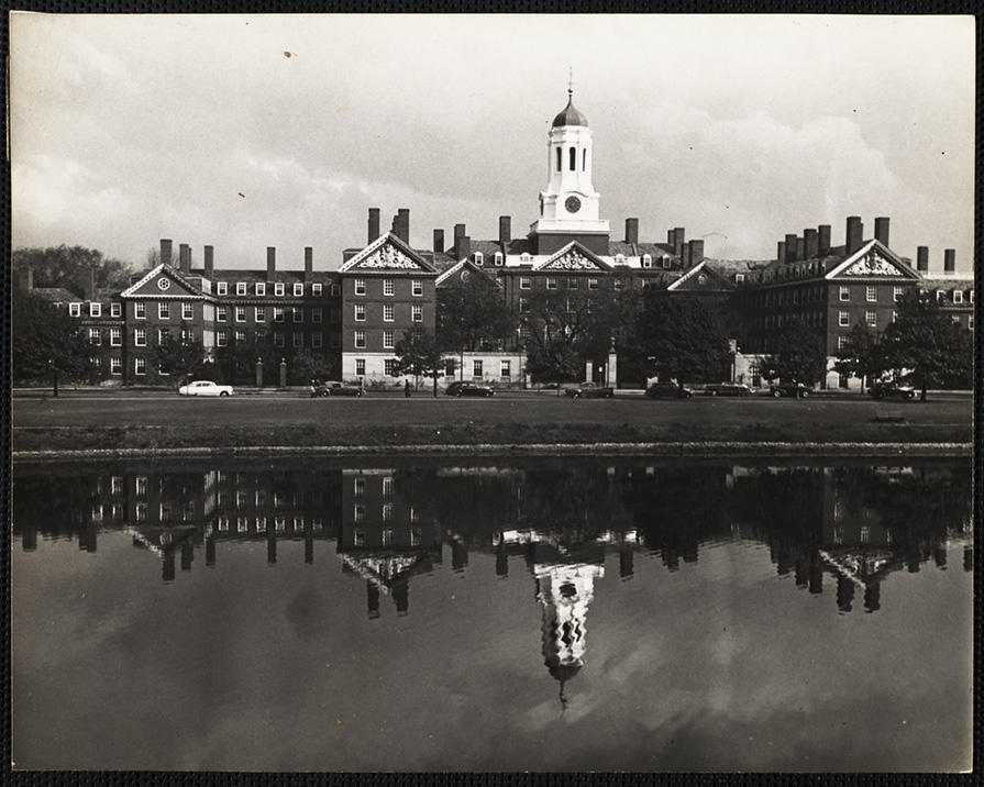 black and white photo of the Dunster tower reflecting onto the Charles river